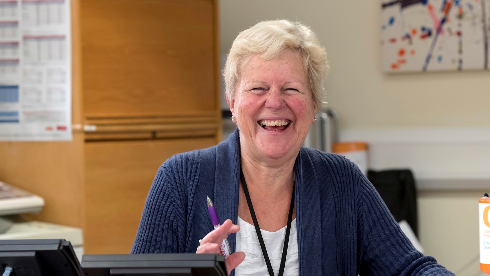 A female volunteer smiling behind a desk