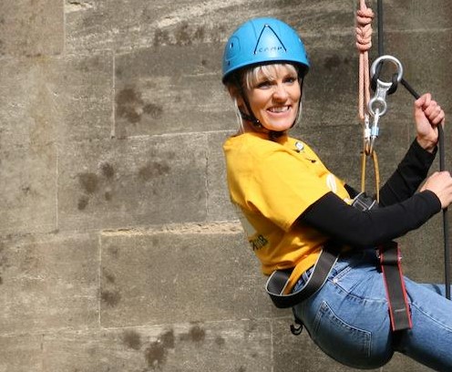 A smiling woman abseiling down the Arundel Tower