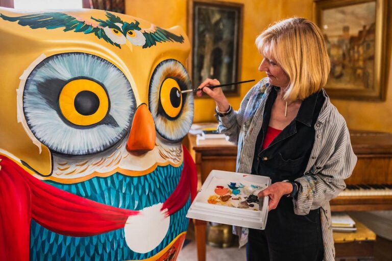 Artist Judith in her home painting her large owl sculpture - Minerva - for the Big Hoot