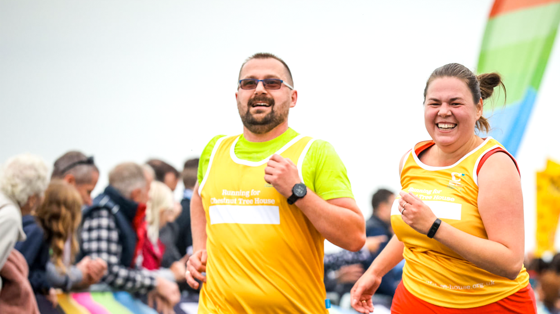 A man and a woman wearing Chestnut Tree House running vests race to the finish line of the Worthing 10k.