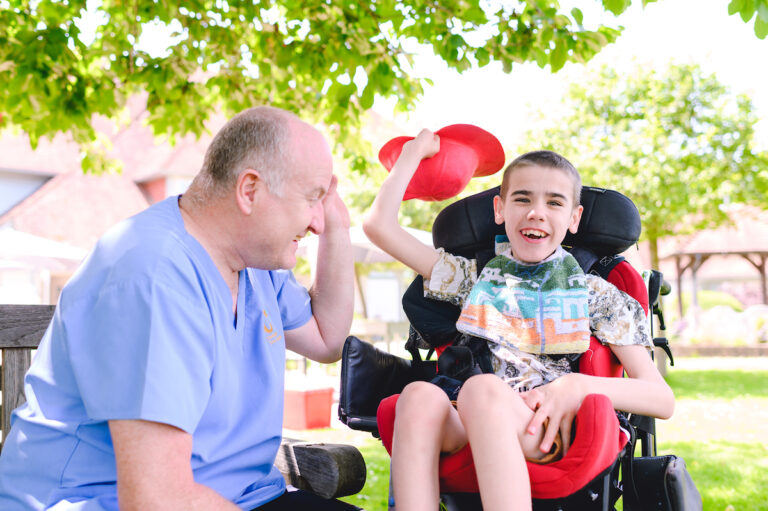 A member of staff with a child in a wheelchair - smiling into the camera
