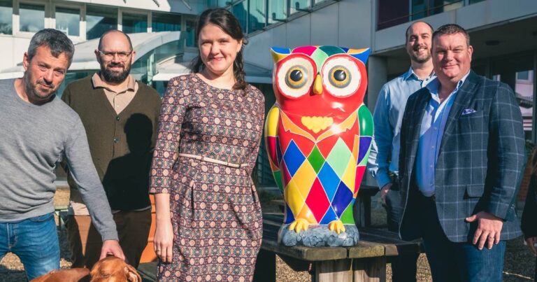 A group of people standing next to a colourful owl.