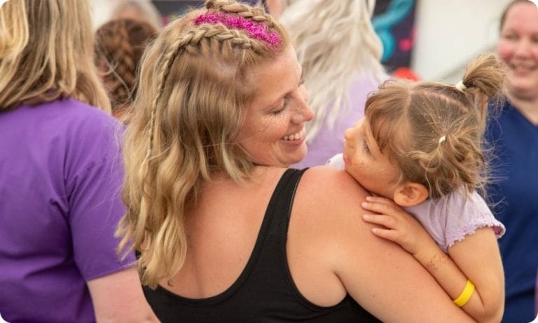 A woman holds a child and they smile at each other
