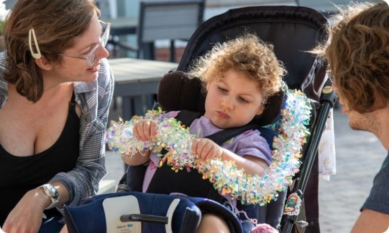 Parents sit with their daughter as she plays with some tinsel