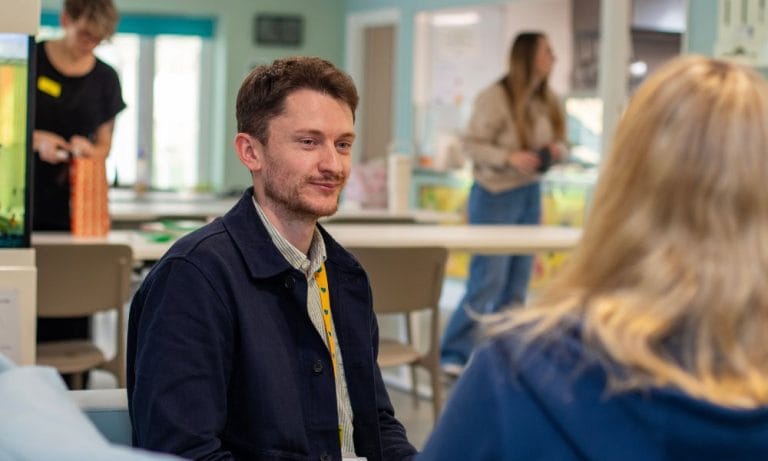 Jonathan, a social worker and child and family support team lead, is pictured in conversation with a woman whose back is facing the camera.