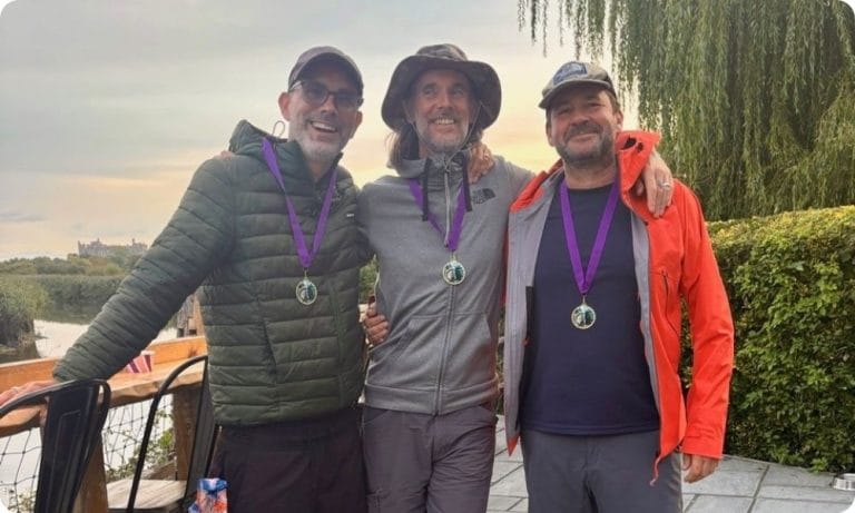 Simon and two friends wear medals and smile for the camera after one of their events