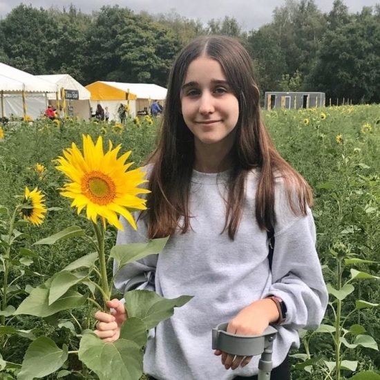 Lola stands in a field of sunflowers