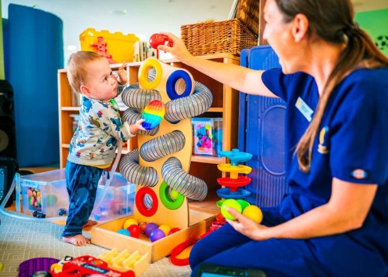 a child playing with a colourful toy with a member of the care team at Chestnut