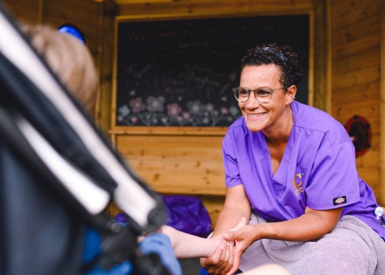 a member of the care team giving a child in a buggy a foot rub