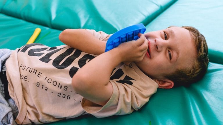 Child at Chestnut Tree house lying on a crash mat and holding a bright blue fidget toy