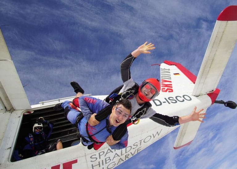 two people jumping out of a plane in tandem