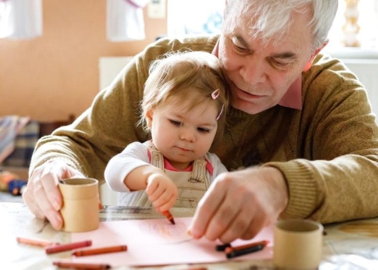 an image of a man and a young child sitting at a table drawing together